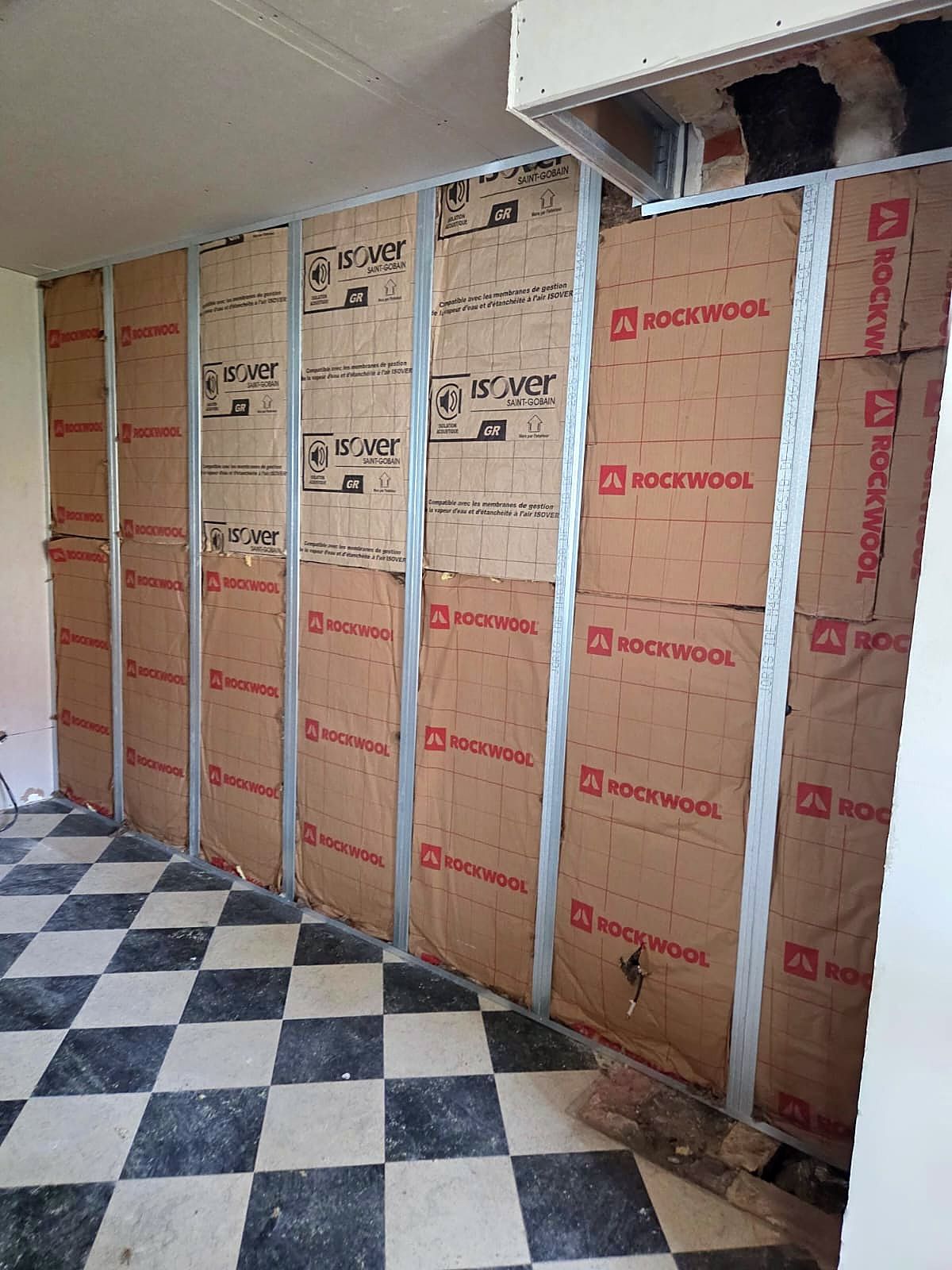 Mur à Dunkerque avant doublage, ossature métallique et panneaux isolants posés, sol en damier