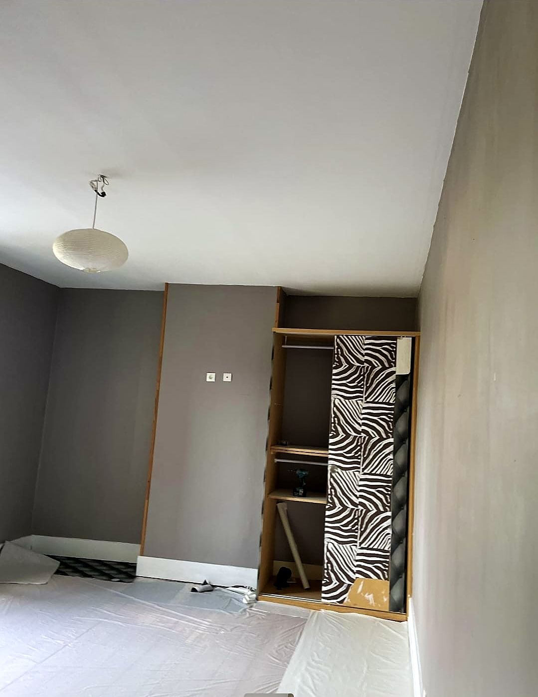 Chambre à Dunkerque avant peinture, murs gris et sol protégé par une bâche